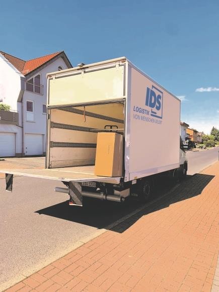 Offener Lieferwagen mit einer Ladung Kartons auf einer Wohnstraße.