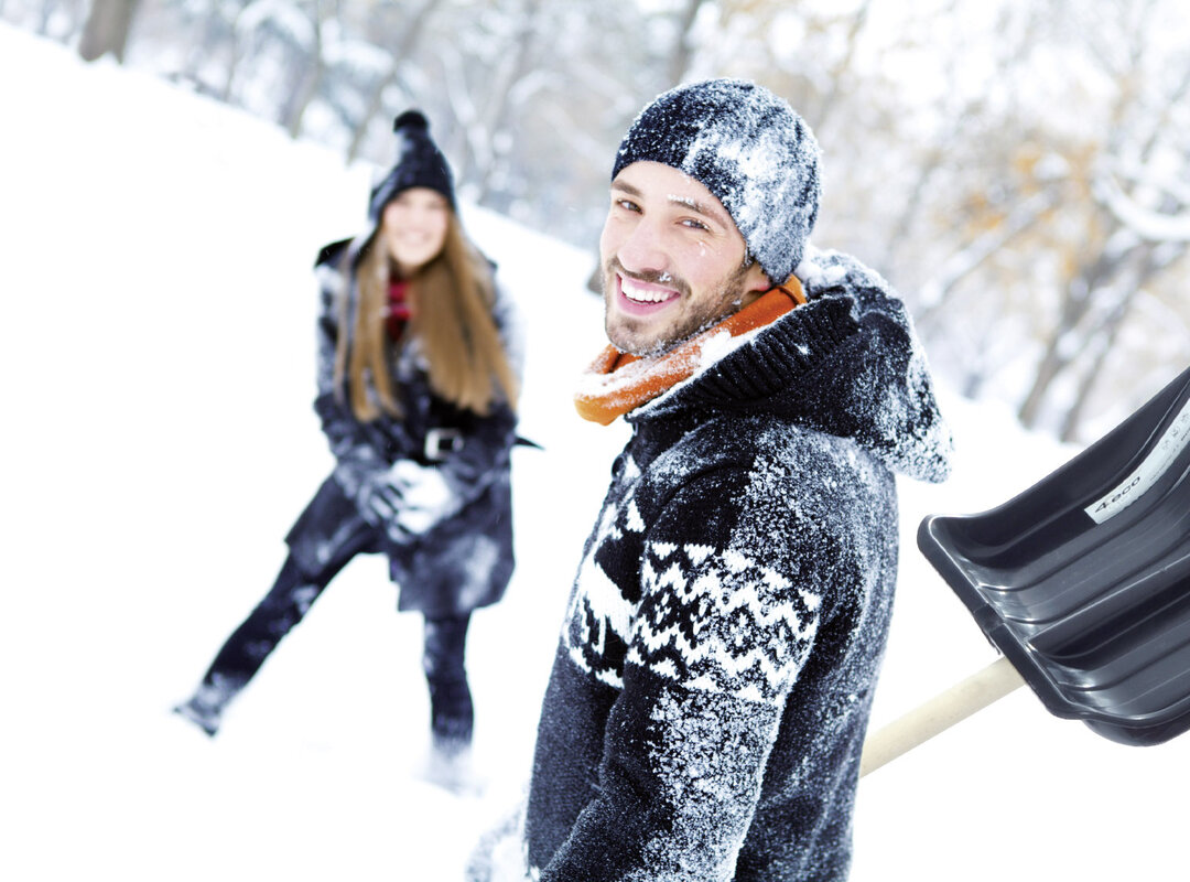 2 Menschen die mit Schnee bedeckt sind und Schneeschaufeln in der Hand haben.