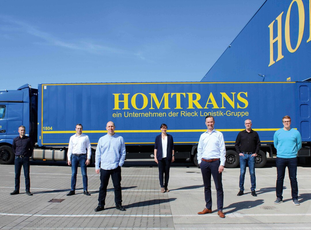 v.l.n.r. Frank Bittner, Ronny Zellhorn, Frederick Polomski, Stephanie Dittberner, Andreas Engelke, Stefan Loschinski, Carsten Strohecker vor einem Lkw von Homtrans.
