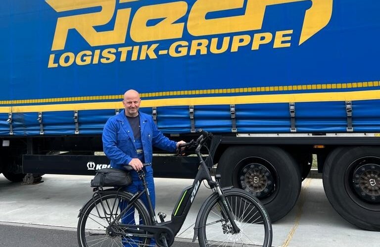 Ein Mitarbeiter von Rieck mit dem Job-Rad vor einem Lkw.