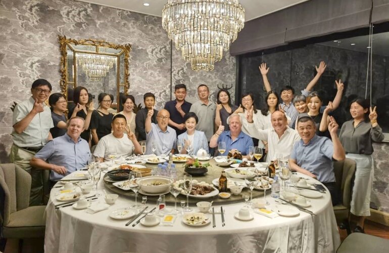 Eine Große Gruppe von Menschen an einem runden Tisch mit Essen drauf.