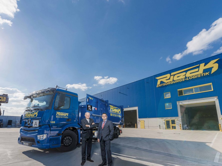 2 Männer vor dem Rieck-Gebäude, wo ein Rieck-Lkw vor steht.