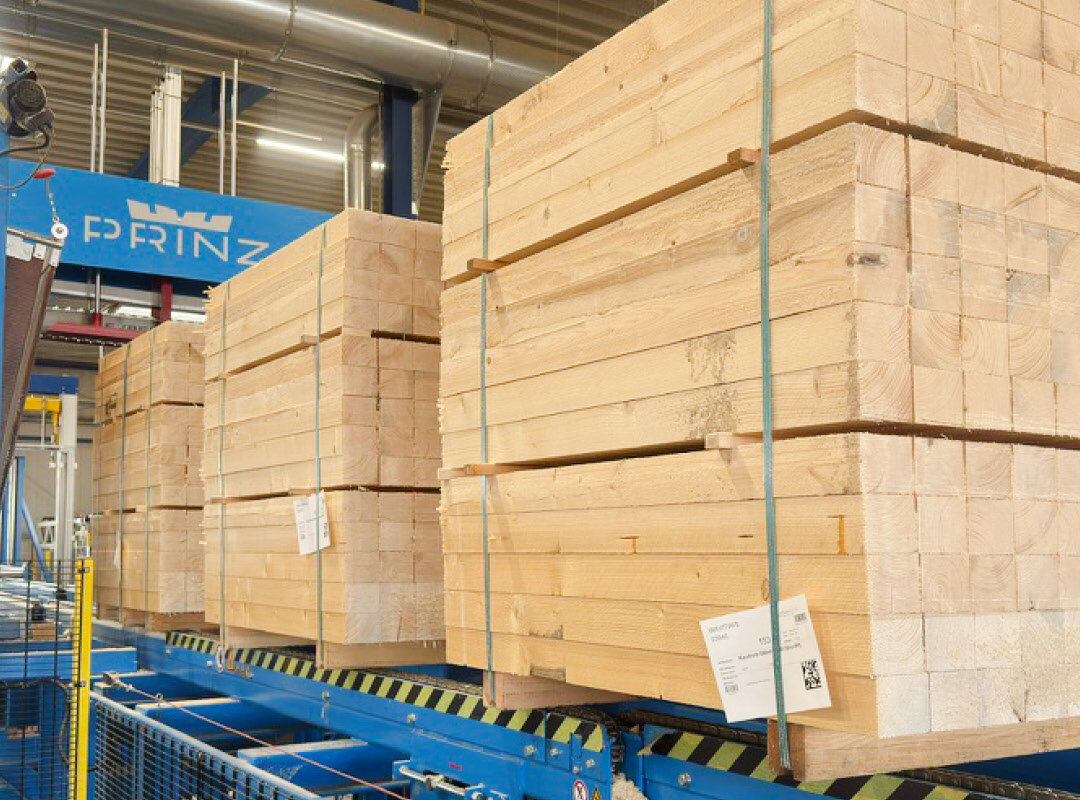 Große Stapel von Holzbohlen in einer Fabrikhalle.