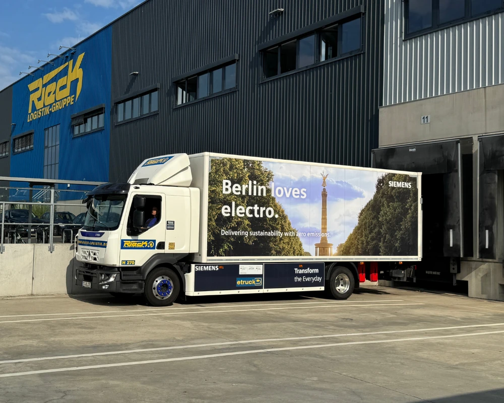 LKW mit Werbebanner "Berlin loves electro" vor Lagerhalle.