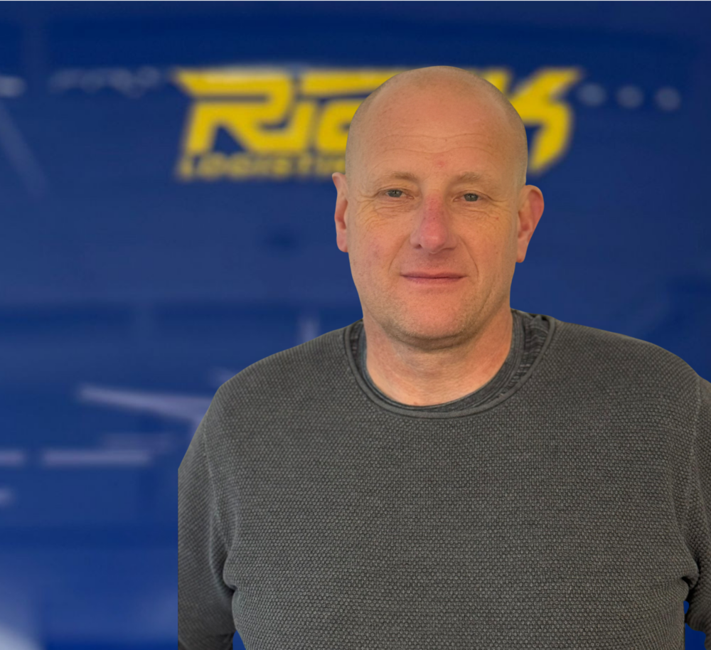 Mann mit grauem Pullover vor blauem Hintergrund mit gelbem Schriftzug.